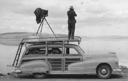 Ansel Adams on roof platform from behind, lake in background, full rack system visible